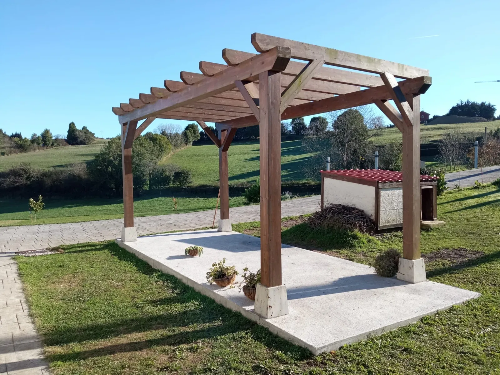 Construcción de solera de hormigón y pérgola de madera en jardín.
